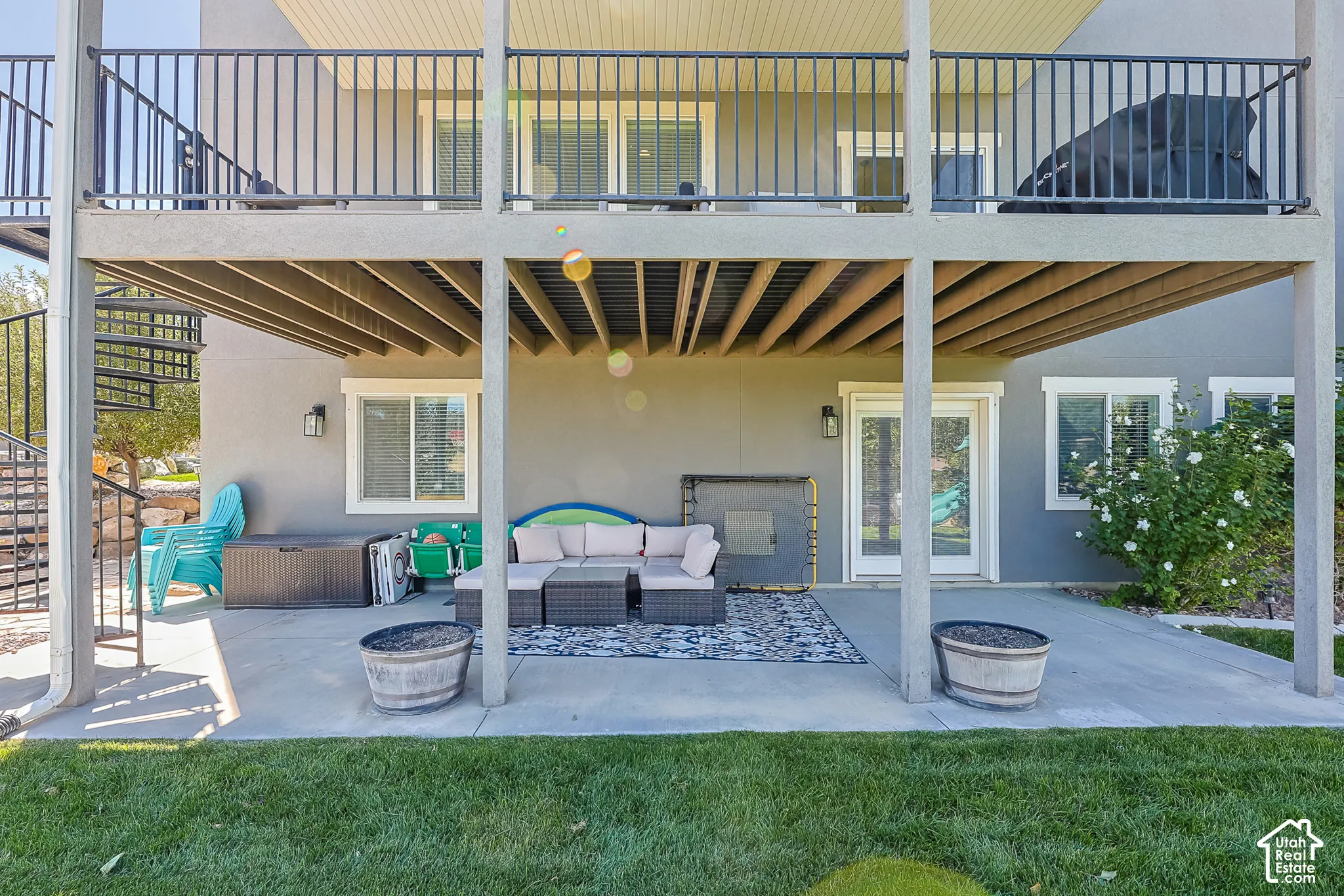 Expansive patio space with a concrete surface, covered by an upper-level deck