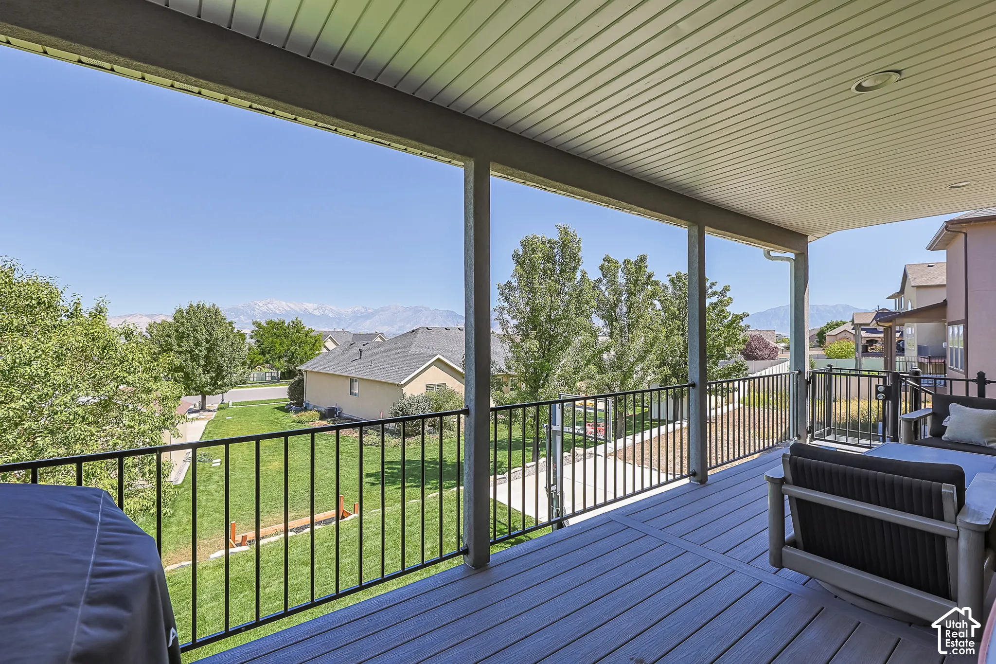 Covered outdoor deck with composite decking, black metal railing, and recessed lighting