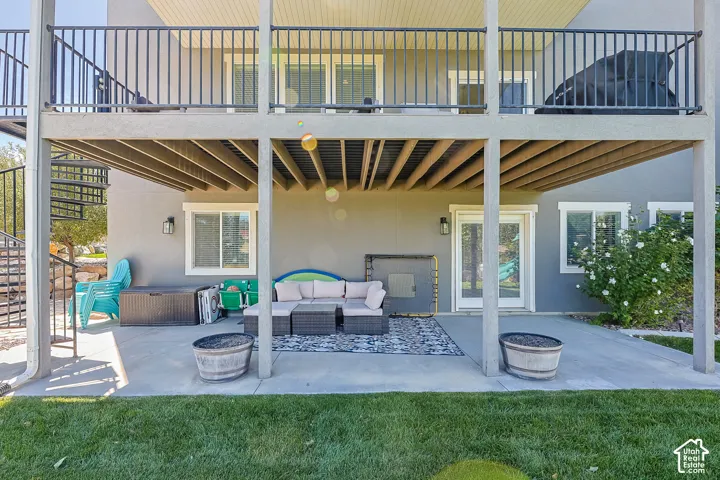 Expansive patio space with a concrete surface, covered by an upper-level deck