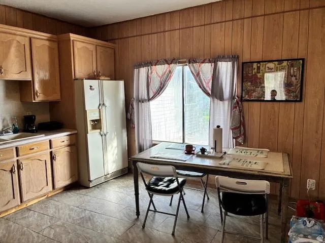 Wood-paneled wall accents, wood-finish cabinetry, built-in sink, and tile flooring