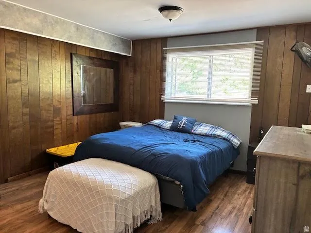 Wood-finish flooring, wood paneling, flush mount ceiling light, and a window with blinds