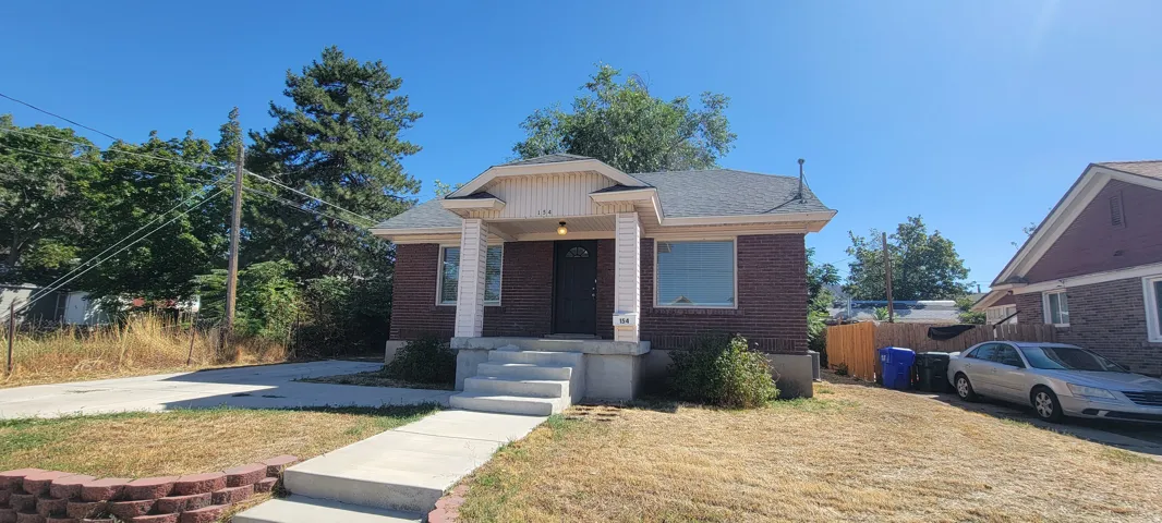 Brick exterior with a covered entry, concrete walkway, and paved driveway