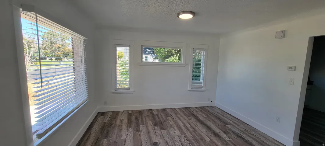 Wood-finish flooring, multiple windows with blinds, recessed ceiling light, and crisp white walls