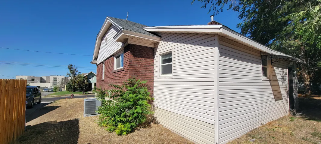 Brick and siding exterior with a pitched roof, featuring a window and an outdoor HVAC unit