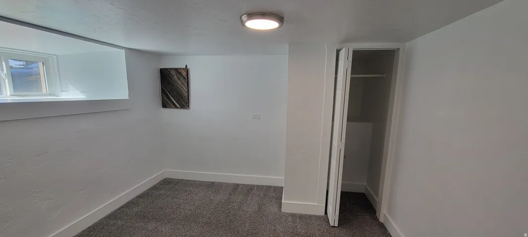 Carpeted room featuring a single window, recessed closet, and a flush-mount ceiling light