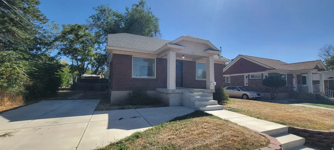Brick exterior with a covered front porch featuring square columns, a concrete walkway, and a concrete driveway