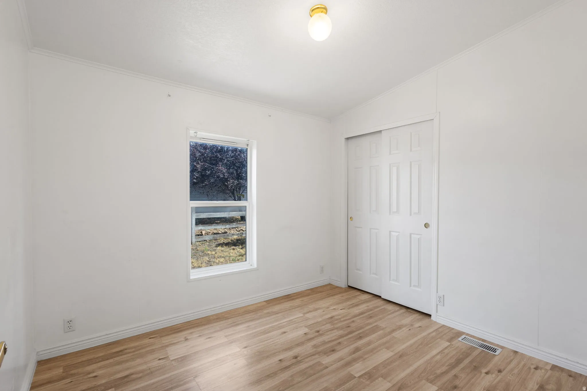 Wood-finish flooring, white walls, and a window with a white frame
