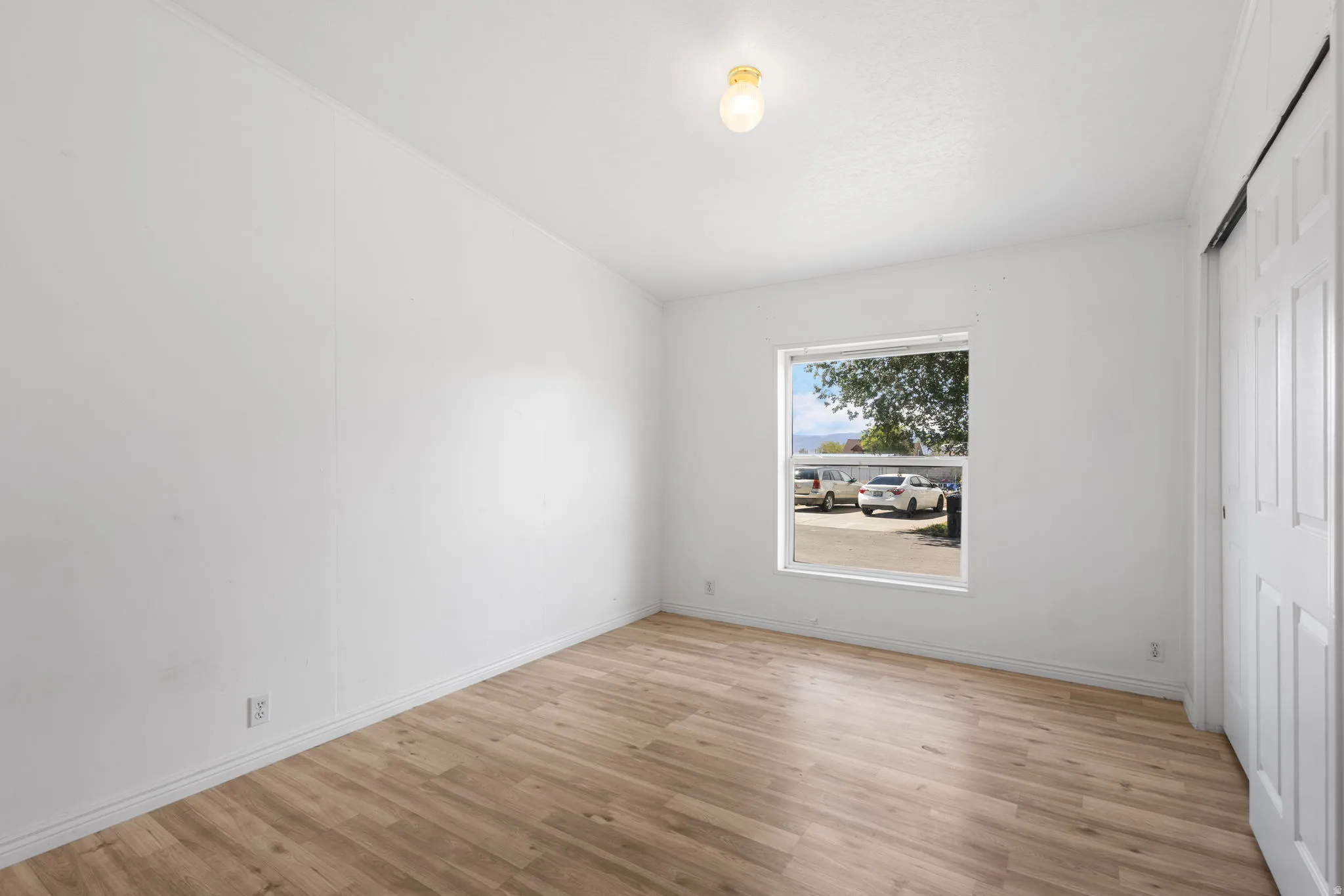 Wood-finish flooring, white walls, and a window providing exterior views