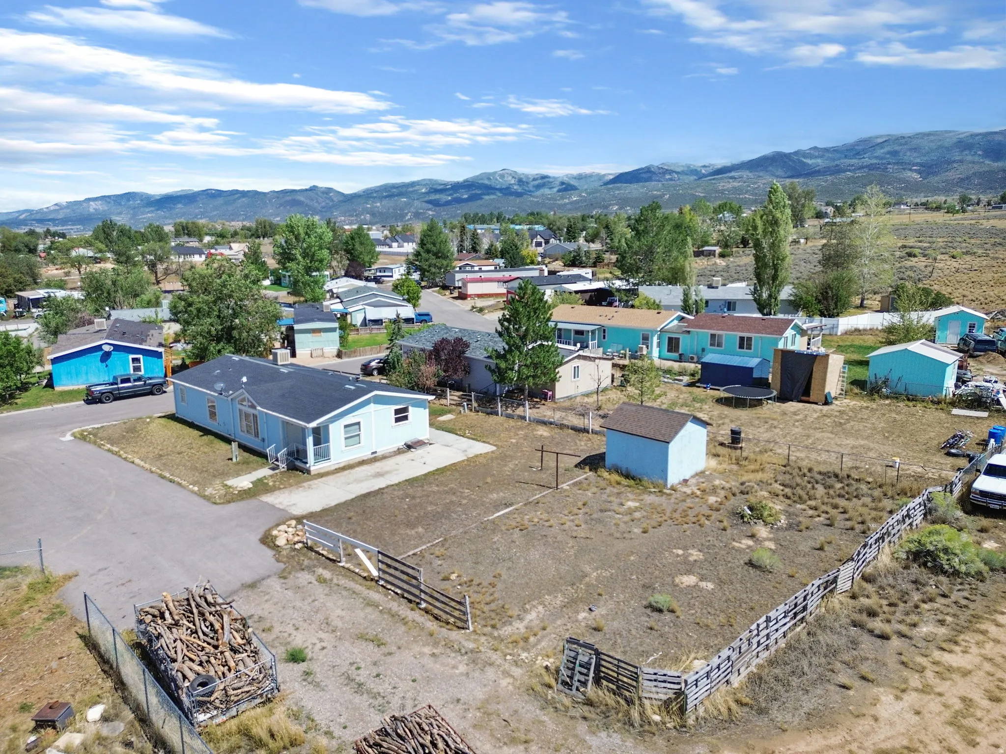 Single-story residence featuring a paved driveway, a fenced lot, and an additional shed structure