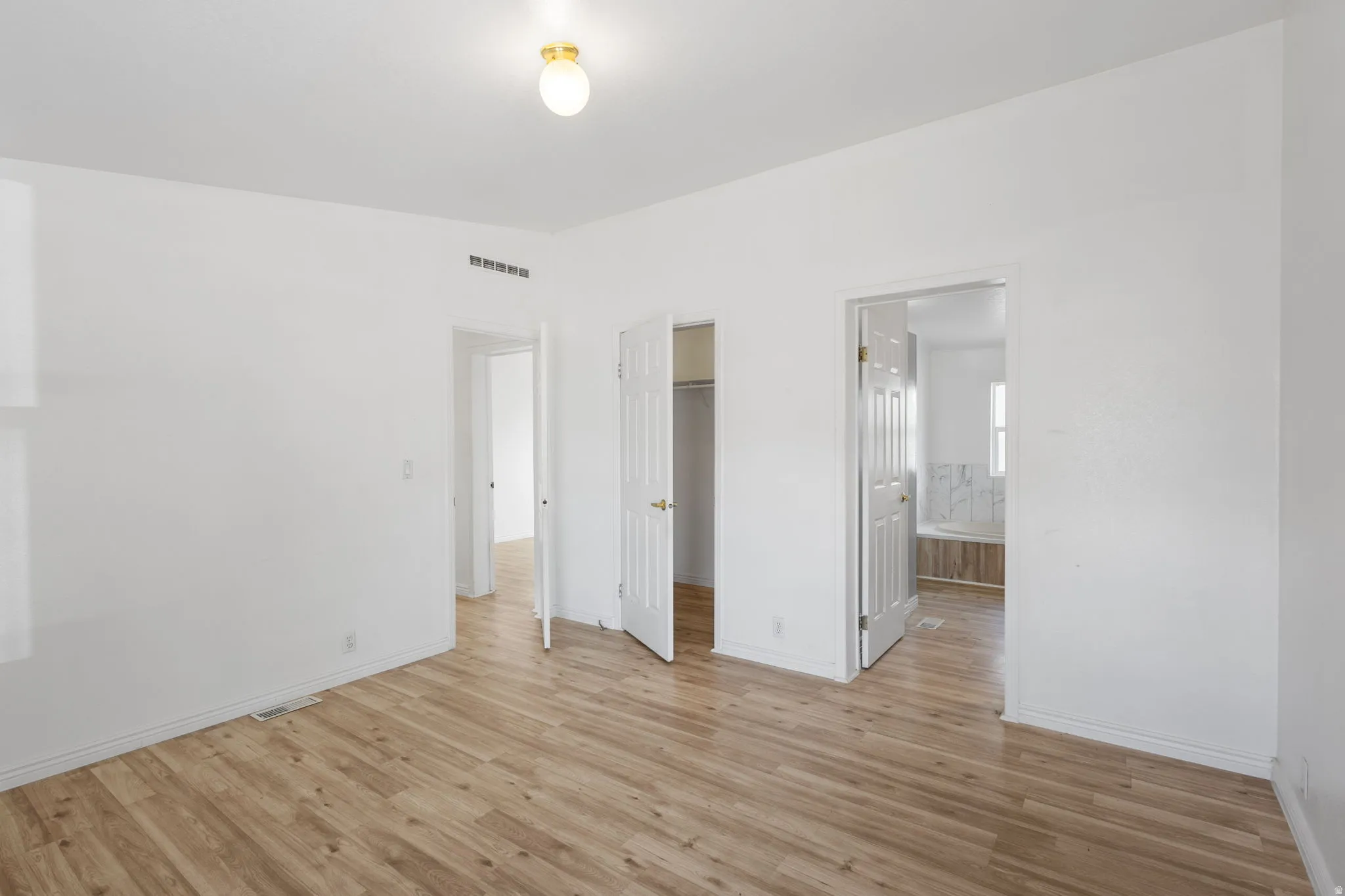 Wood-finish flooring with white walls and a flush-mount ceiling light fixture
