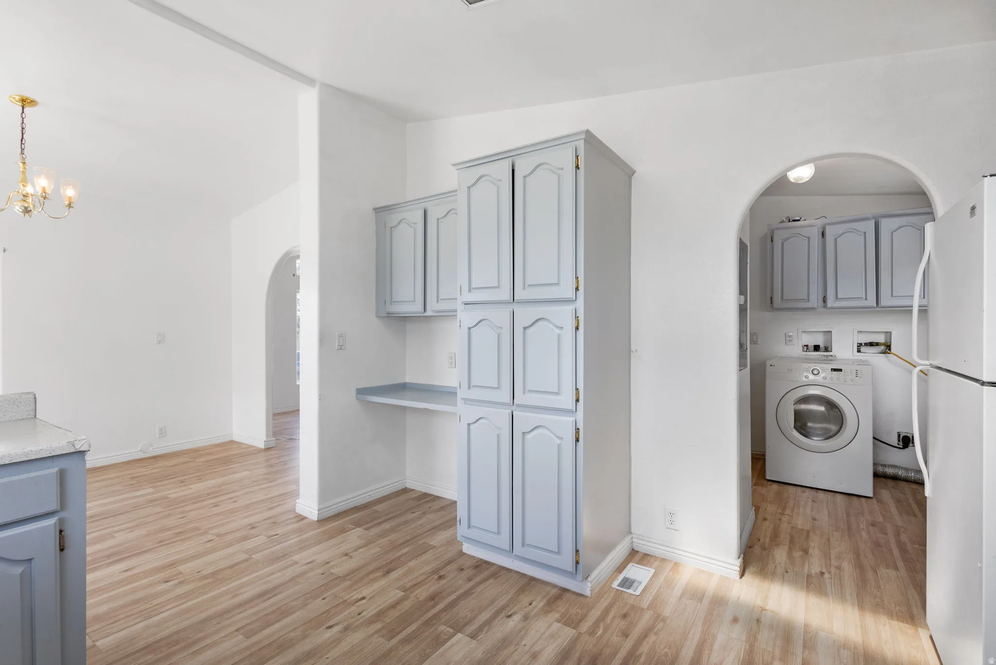 Wood-finish flooring throughout, light-toned cabinetry, built-in desk, and an arched entryway