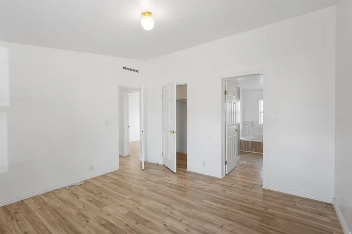 Wood-finish flooring with white walls and a flush-mount ceiling light fixture
