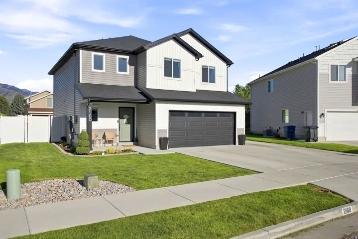 Two-story residence featuring a two-tone exterior, attached two-car garage, concrete driveway, and a white privacy fence