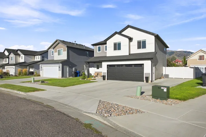 Two-story residence with a two-car garage, concrete driveway, and white privacy fence