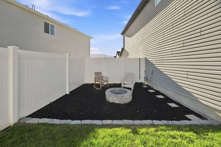 Enclosed outdoor space featuring a stone fire pit, dark ground cover, and stepping stones