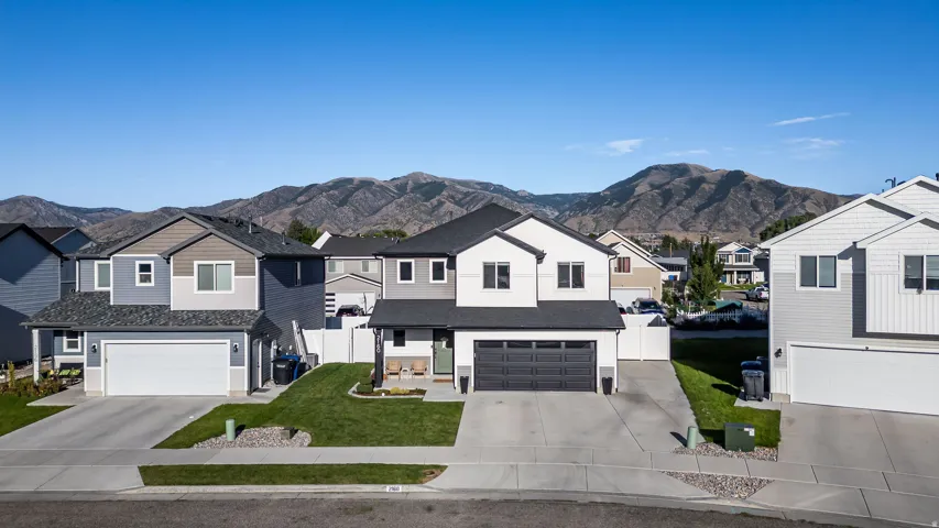 Contemporary two-story residence with a dark gray roof, white and gray siding, and a two-car garage