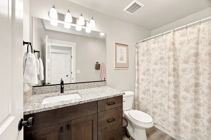 Vanity with a granite-style countertop, undermount sink, and dark wood-finish cabinetry