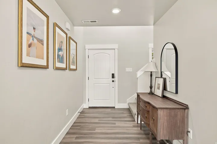 Wood-finish flooring with a white trim, recessed ceiling lighting, and a paneled entry door