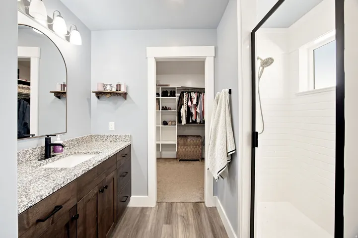 Wood-finish flooring with a vanity featuring a granite-style countertop and an undermount sink