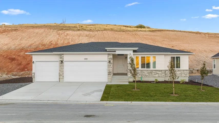 Modern exterior featuring horizontal siding, stone accents, a dual garage, a covered entry, and a manicured lawn