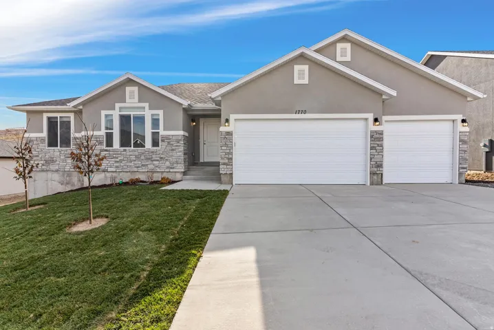 Contemporary stucco exterior with stone accents, a multi-pane front window, and an attached two-car garage