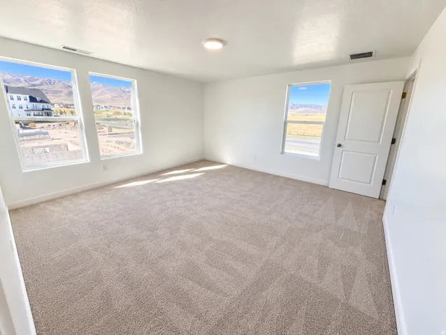 Three large windows, neutral-toned carpeting, a contemporary flush mount light fixture, and a white two-panel door