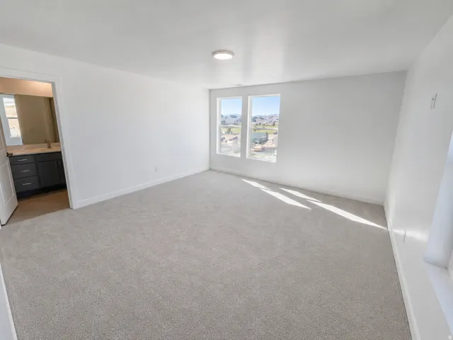 Recessed lighting, light-toned carpeting, dual windows, and an en suite bathroom with a dark wood vanity and light countertop