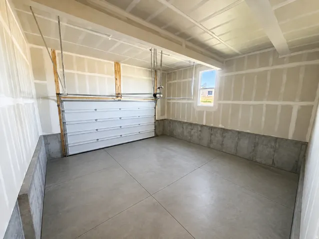 Spacious garage featuring a concrete floor, window, and an overhead door