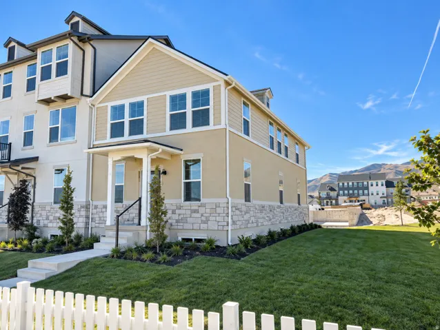 Exterior featuring stone and stucco finishes, multiple windows, a covered entry, and a manicured lawn