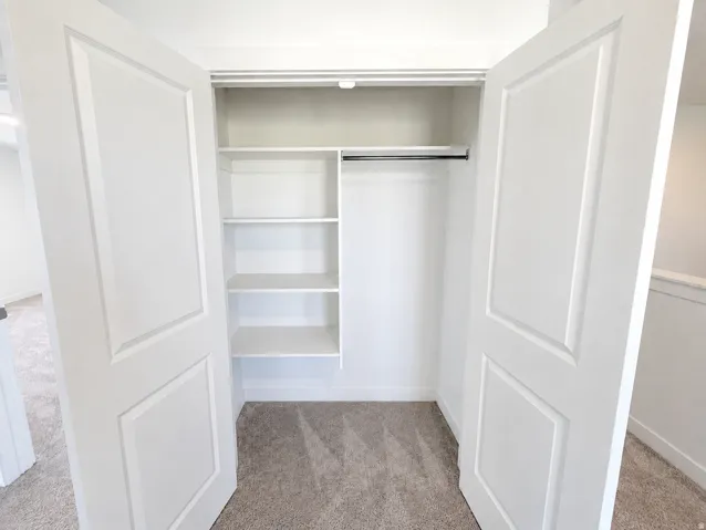Double panel interior doors open to a closet featuring built-in shelving, a clothes rod, and carpeting