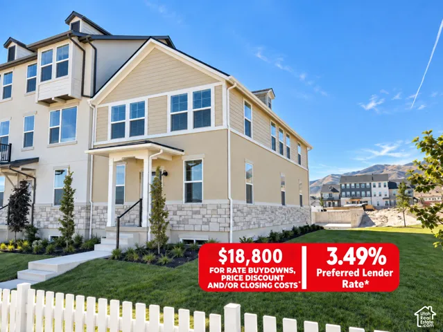 Multi-story exterior featuring tan horizontal siding, stone veneer base, covered entryway, and mountain scenery