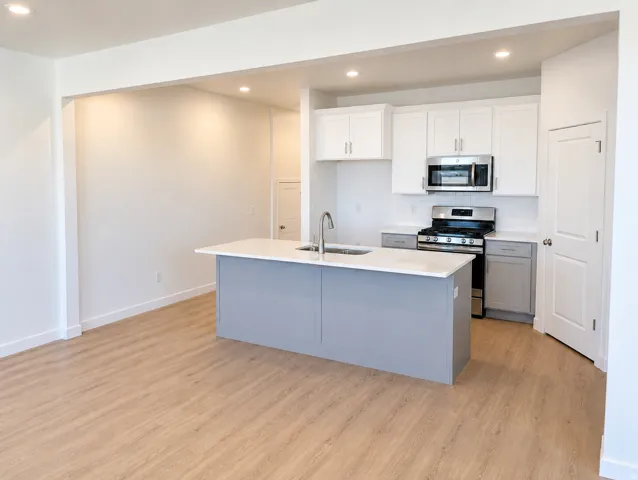 Kitchen featuring a central island with countertop, white cabinetry, stainless steel appliances, and a tile backsplash
