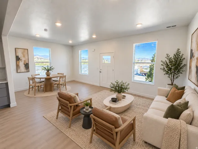 Recessed lighting, light wood-finish flooring, white paneled walls, multiple windows, and a white paneled door