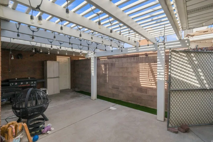 Patio featuring a white pergola, string lighting, concrete flooring, and privacy walls