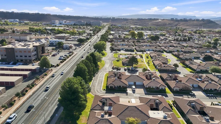 Residential community featuring multiple single-story structures with tiled roofs, surrounding green spaces, and paved streets