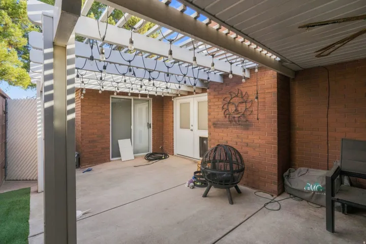 Paved patio with a slatted pergola, brick exterior walls, and a sliding glass door