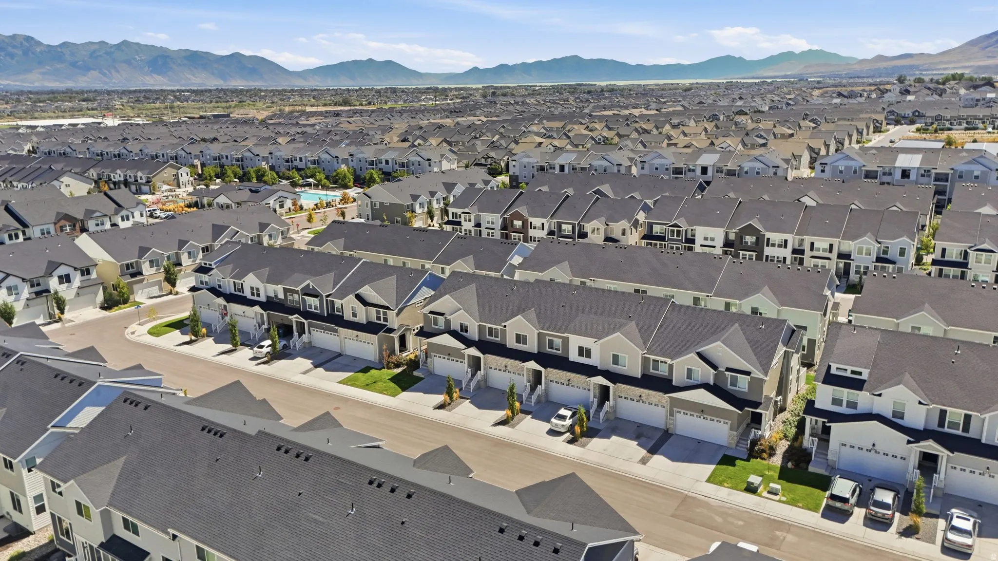 New construction townhomes with attached garages, manicured landscaping, and a community pool