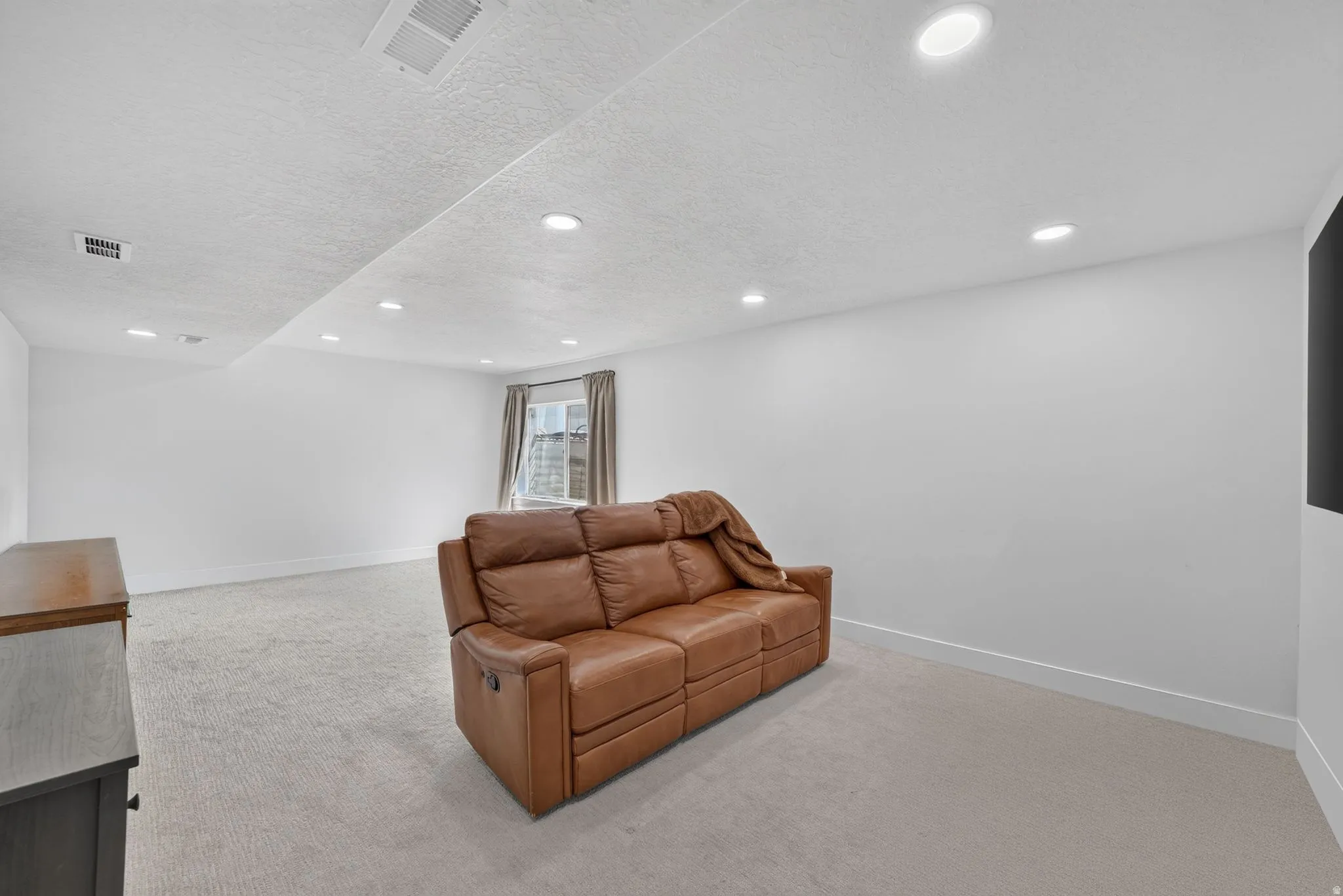 Recessed ceiling lighting, carpeted flooring, window with drapes, painted walls, wall-mounted display