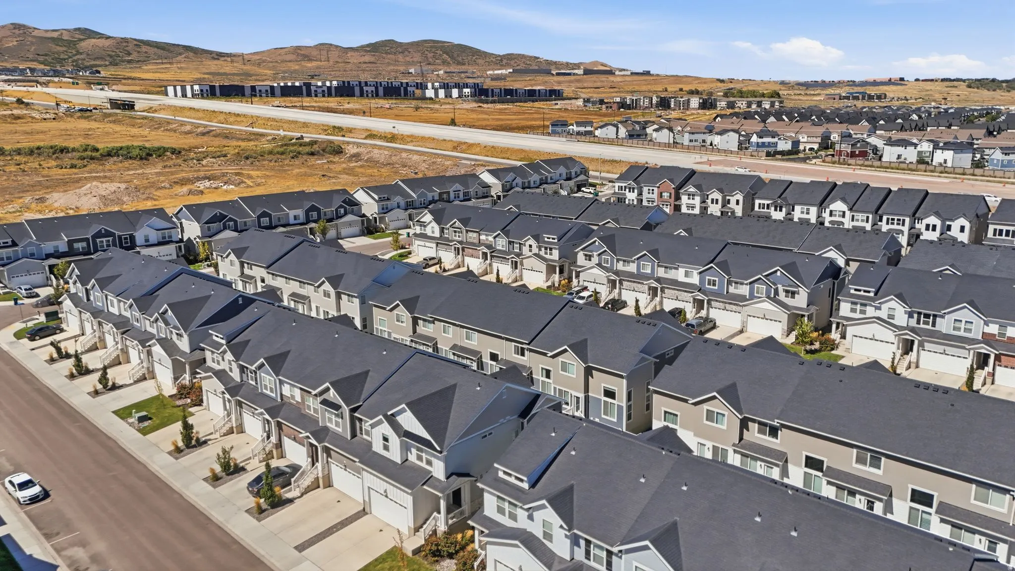 Townhome development featuring a consistent architectural style, dark asphalt shingle roofs, attached garages, and a paved street