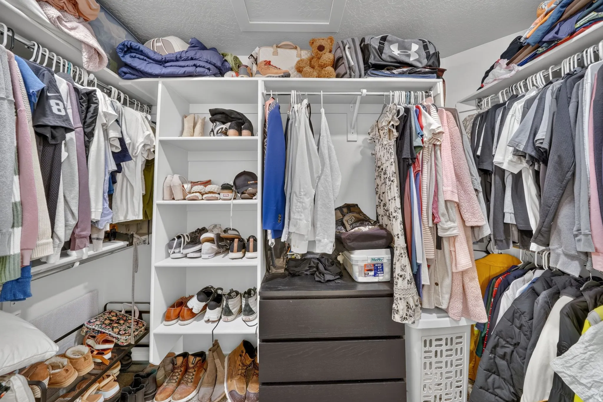 Walk-in closet featuring extensive built-in shelving, multiple hanging rods, and integrated drawer storage