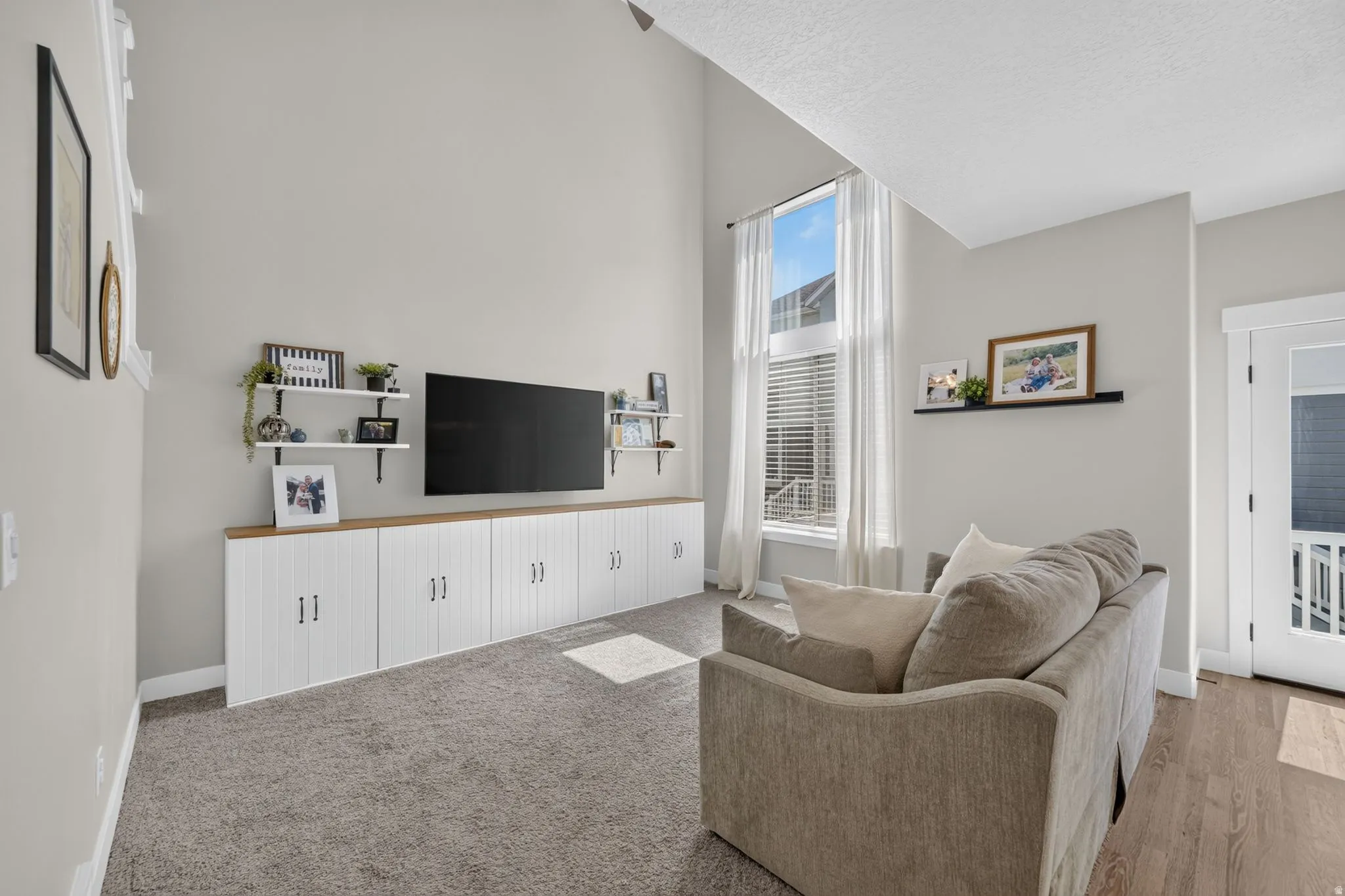Vaulted ceiling, built-in cabinetry with wood-finish countertop, tall windows with blinds, wood-finish flooring, and light gray wall paint