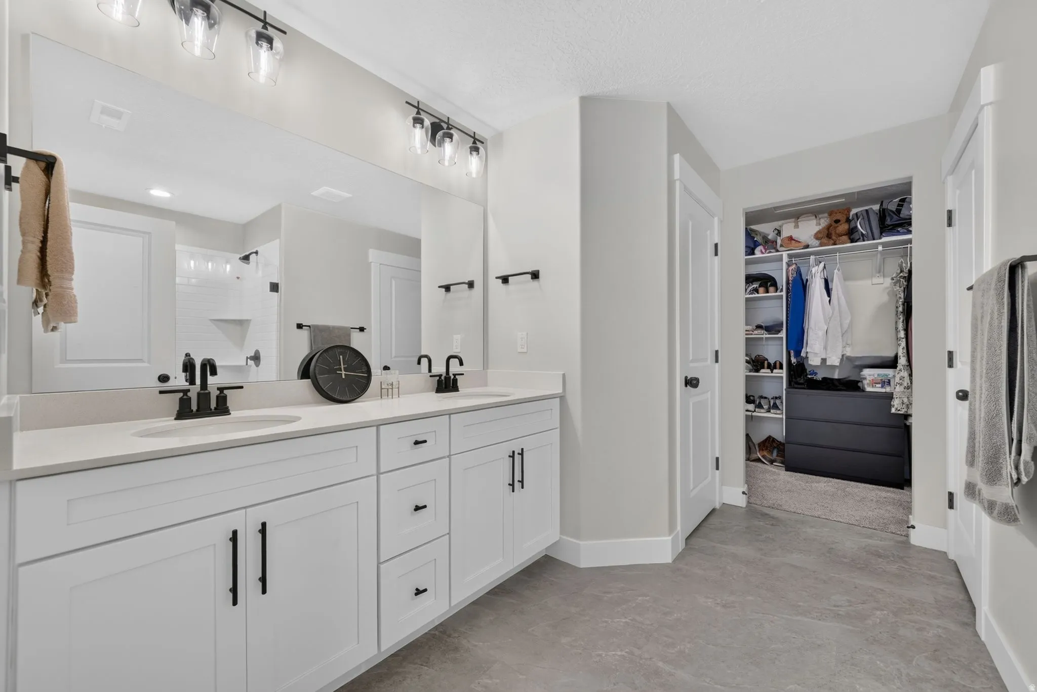 Dual vanity with white cabinetry, matte black hardware, and light-toned countertops