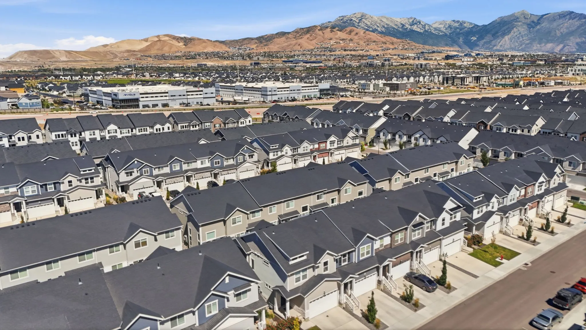 Modern residential development featuring uniform townhomes with attached garages and paved driveways