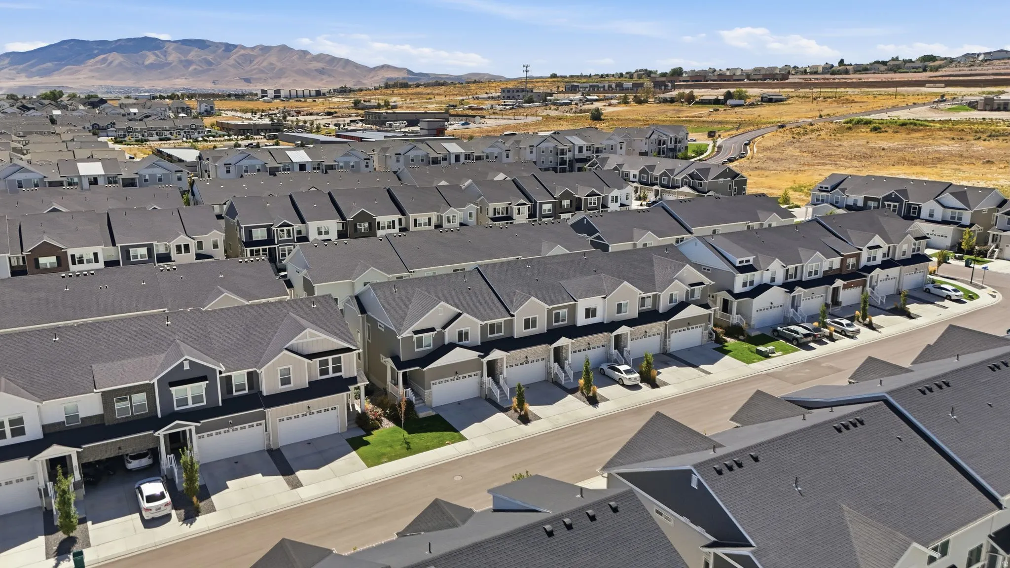 Contemporary townhomes featuring multi-tone exteriors, attached garages, and paved driveways