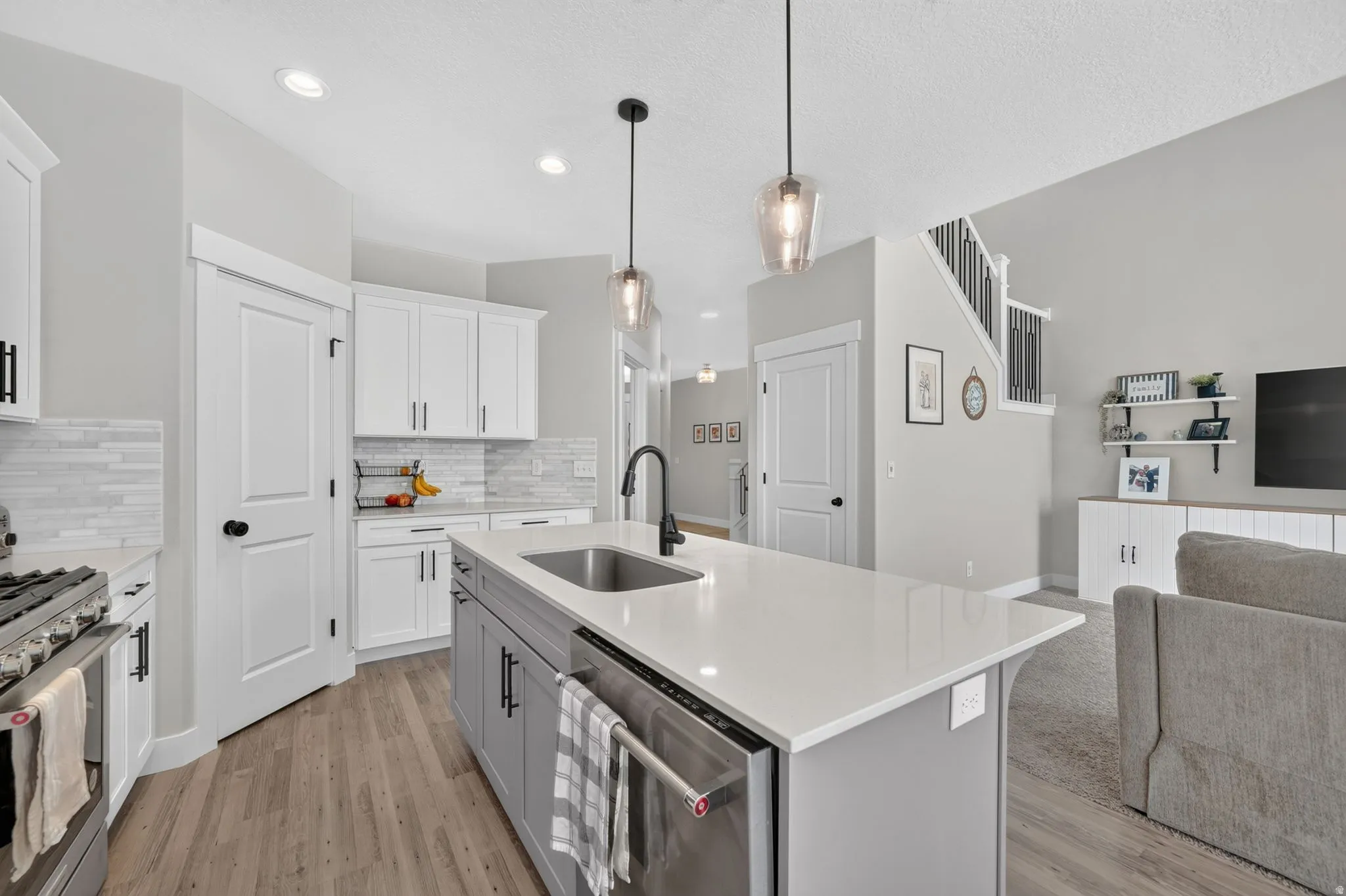 Kitchen featuring a large island with sink, white shaker-style cabinetry, a tile backsplash, stainless steel appliances, and recessed lighting