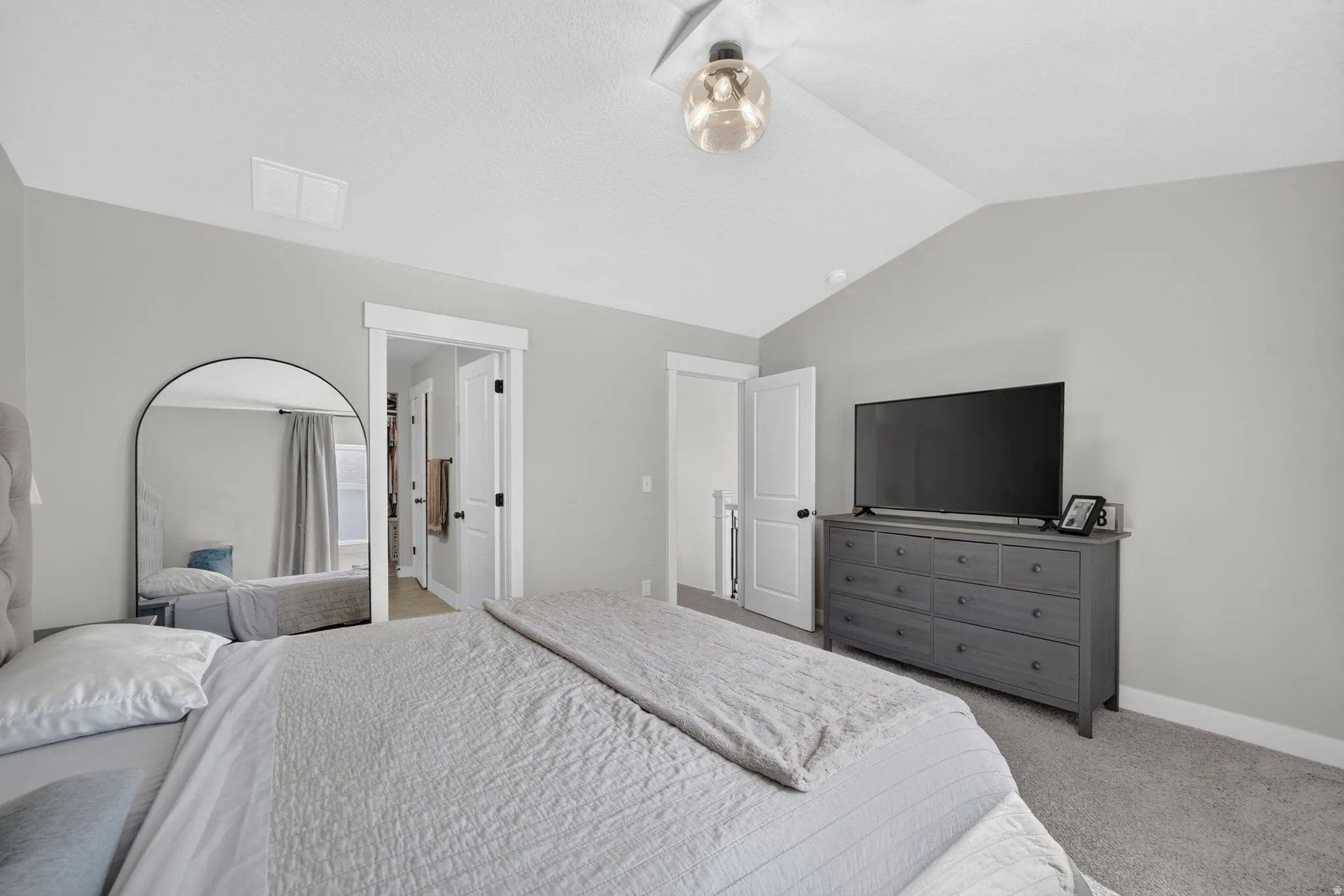 Vaulted ceiling with an attached light fixture, light gray wall paint, and gray carpeting