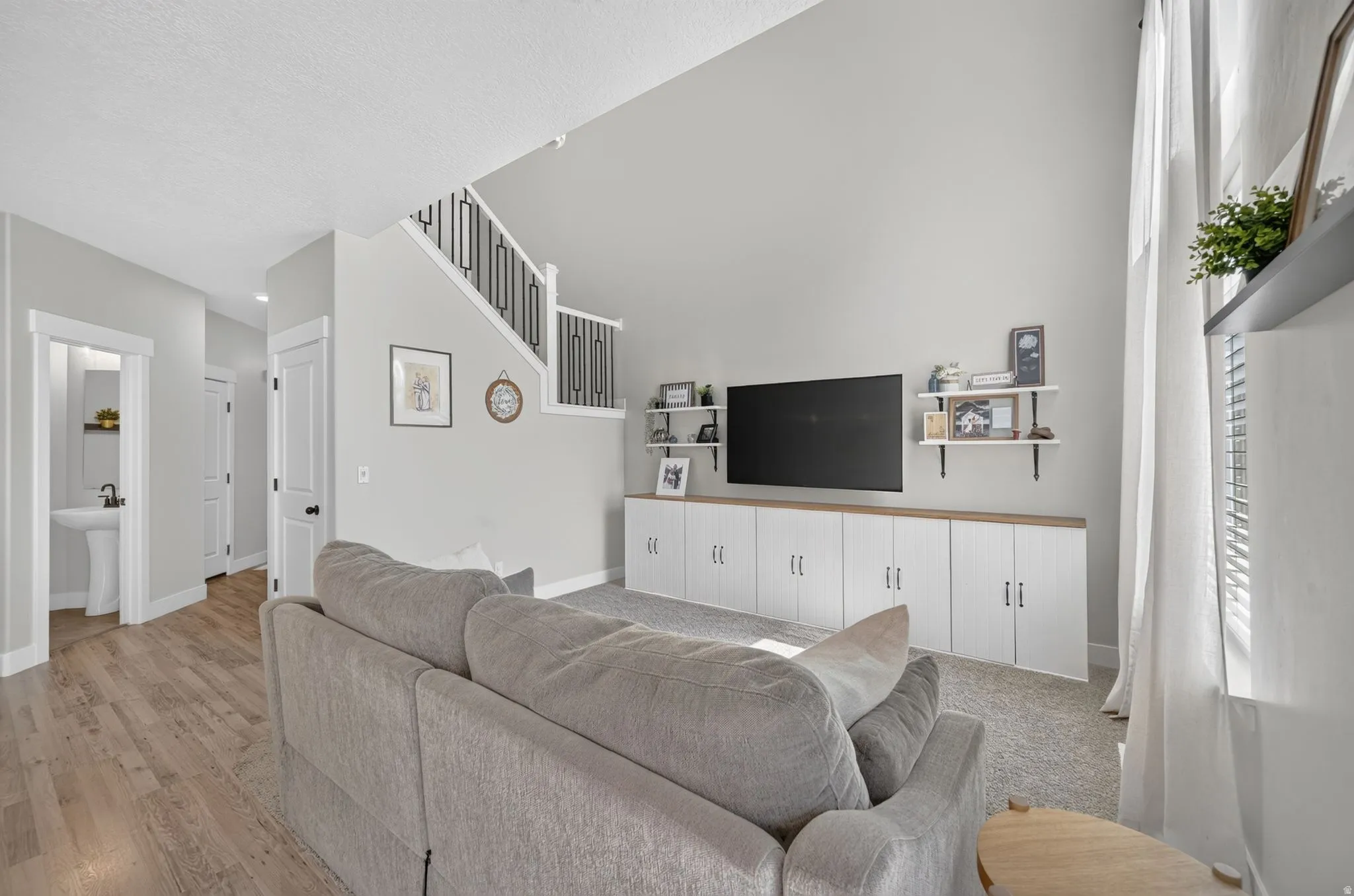 Vaulted ceiling with an open staircase, built-in media storage, and wood-finish flooring