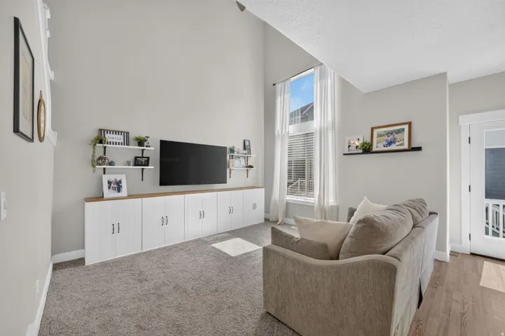 Vaulted ceiling, built-in cabinetry with wood-finish countertop, tall windows with blinds, wood-finish flooring, and light gray wall paint