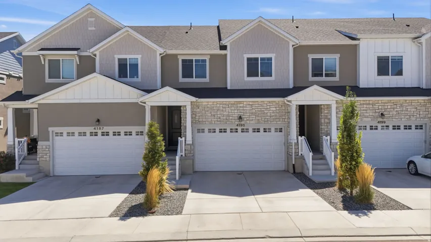 Multi-level exterior with mixed material siding, stone accents, and a two-car garage