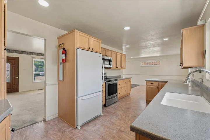 Kitchen featuring light wood cabinetry, stone-finish countertops, tile flooring, and recessed lighting